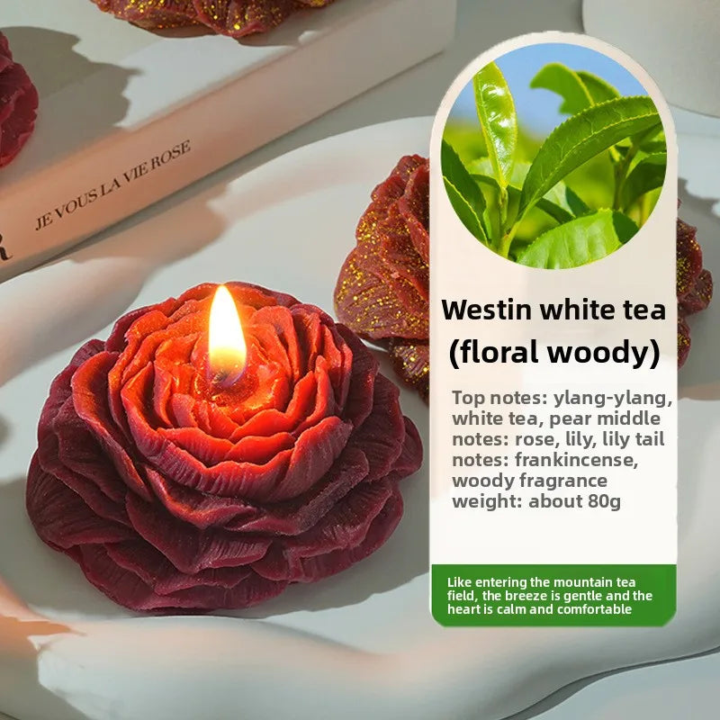 Dunkelrote Rosenkerze in Pfingstform auf weißem Teller neben einem Etikett für Westin White Tea Duft.
