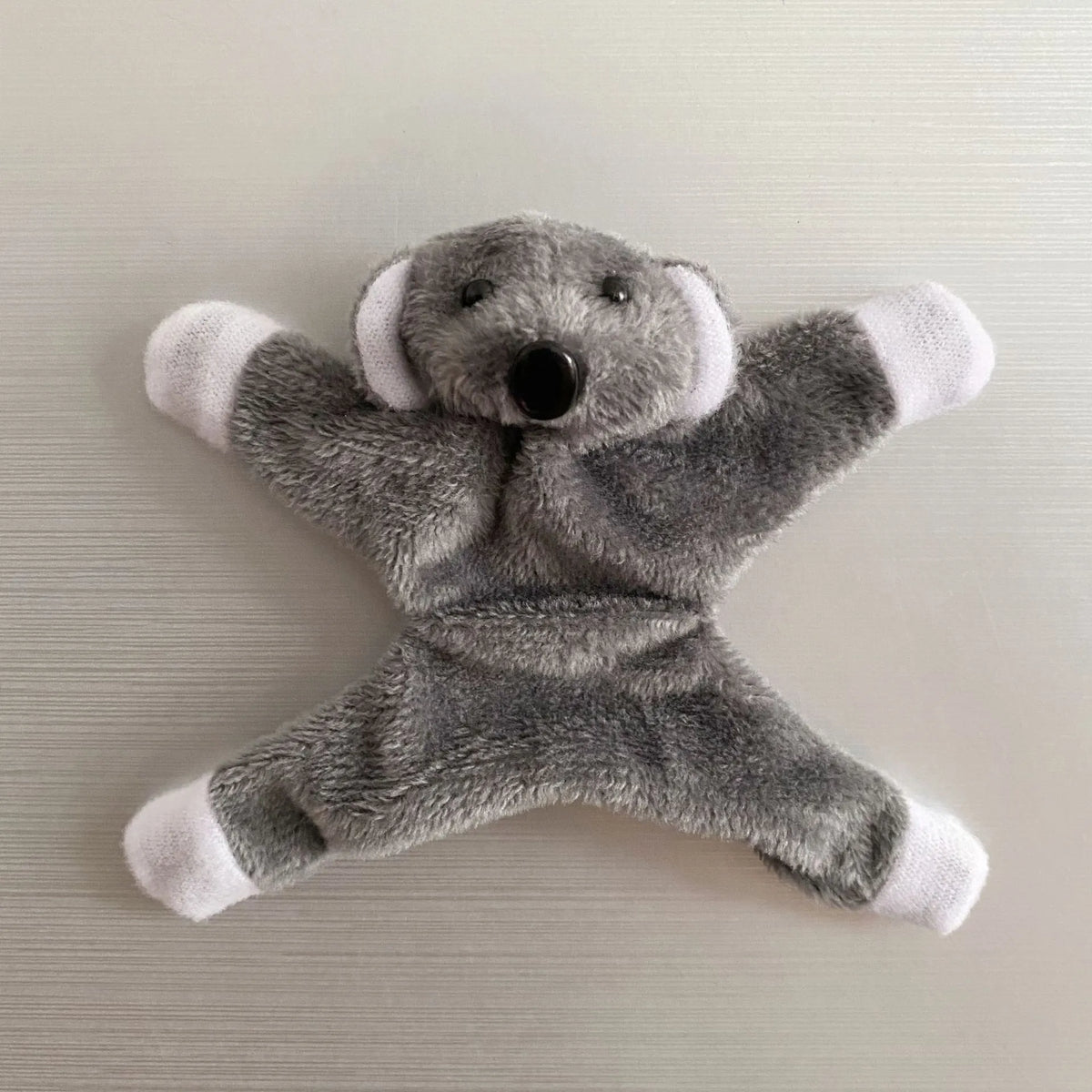 A gray plush elephant toy with white accents, used as a fridge magnet.