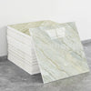 A rectangular slab of light beige and white marble-patterned faux stone tile displayed on a gray floor.