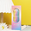 A vertical box of elegant spiral birthday candles in pink and purple hues resting on a white cloth.