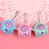 Three colorful mini rock paper scissors keychains with hand gestures hanging against a pink lace background