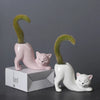 A pink ceramic cartoon cat planter with a green succulent plant emerging from its tail design.