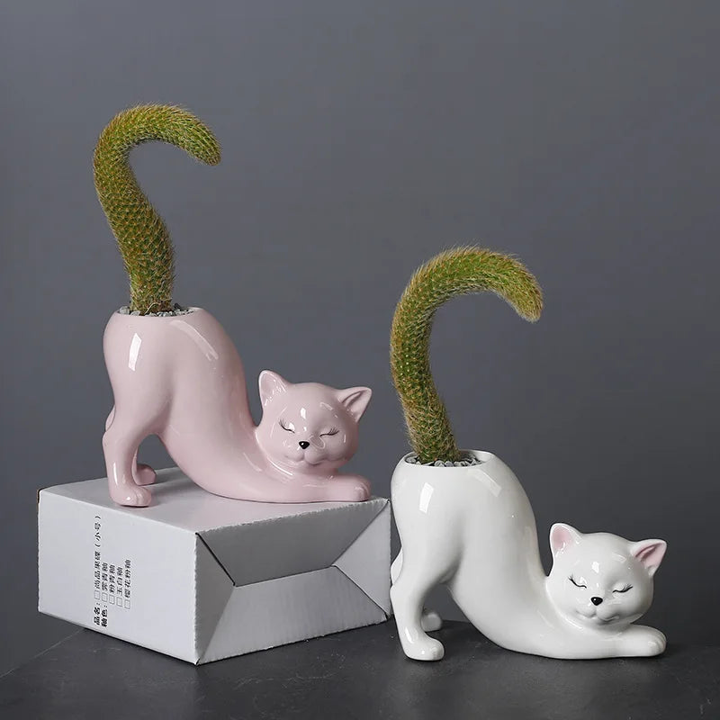 A pink ceramic cartoon cat planter with a green succulent plant emerging from its tail design.