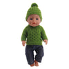 A baby doll wearing a green knitted hat and matching green sweater with dark blue pants.