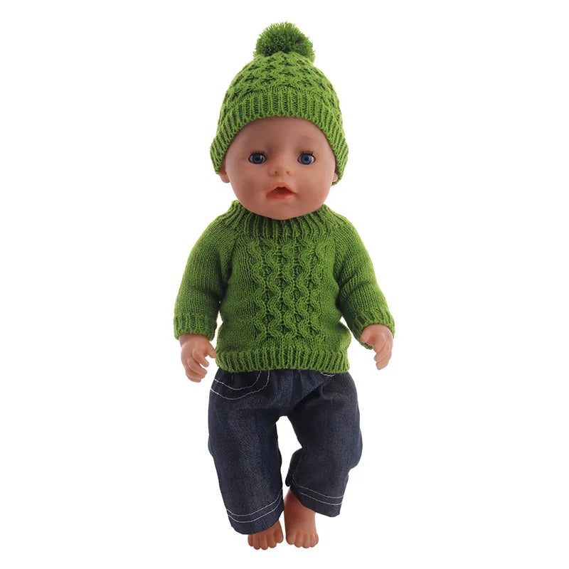 A baby doll wearing a green knitted hat and matching green sweater with dark blue pants.