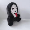 A black plush toy resembling Ghost Face with white facial markings and a red tongue.
