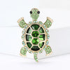 A vintage marine life brooch pin set featuring a gold-toned starfish with green and clear stones.