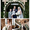 A bride and groom stand under a floral archway decorated with white roses and greenery.