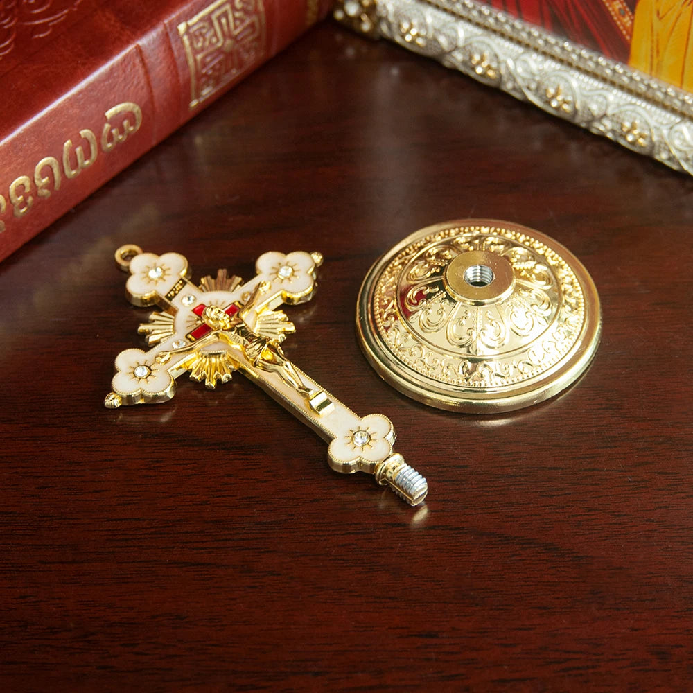 Elegant gold metal Jesus cross ornament with a decorative base on a dark wooden surface.