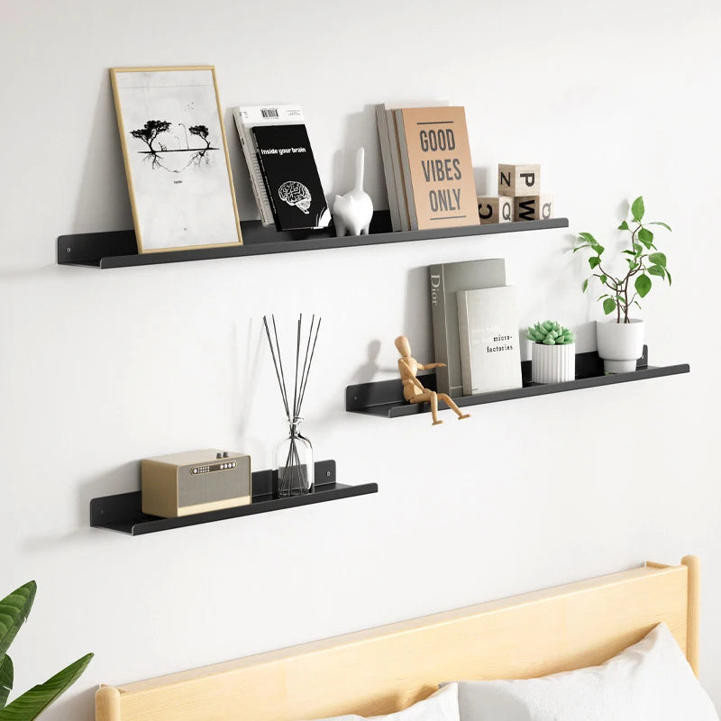 A set of black floating metal wall shelves displaying various decorative items and books.
