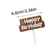 A brown gingerbread stick with white icing spelling out Happy Birthday and a leaf design.