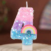 A colorful candle shaped like the number 4 made of pink, purple, and blue glitter and rainbow sequins.