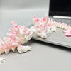 A white and pink cherry blossom dragon miniature figurine lying on a silver laptop.
