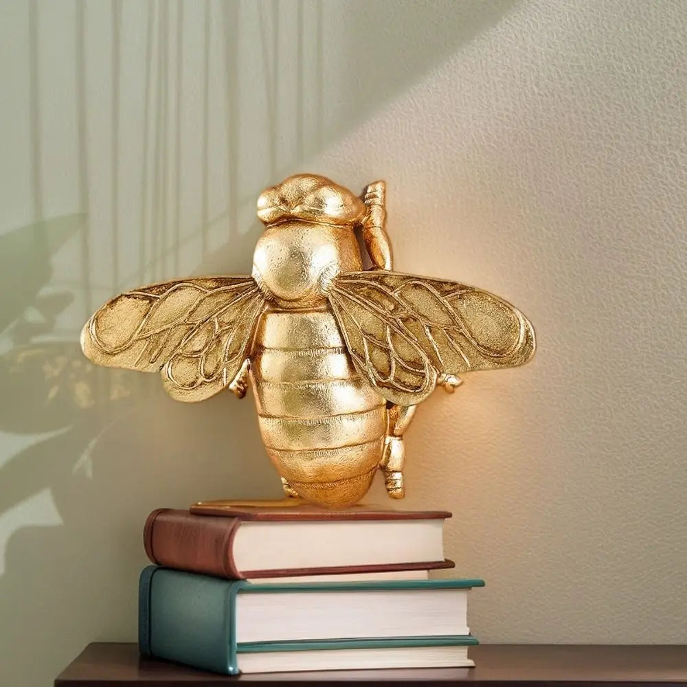 Handgefertigte goldene Bienenwandskulptur auf einem Stapel Bücher.