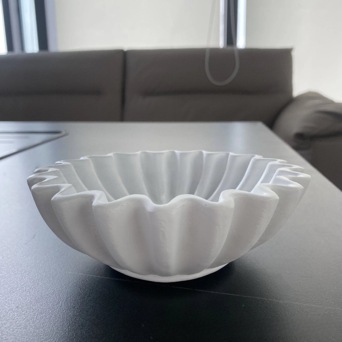 A white lotus leaf resin decorative bowl is displayed on a dark table.