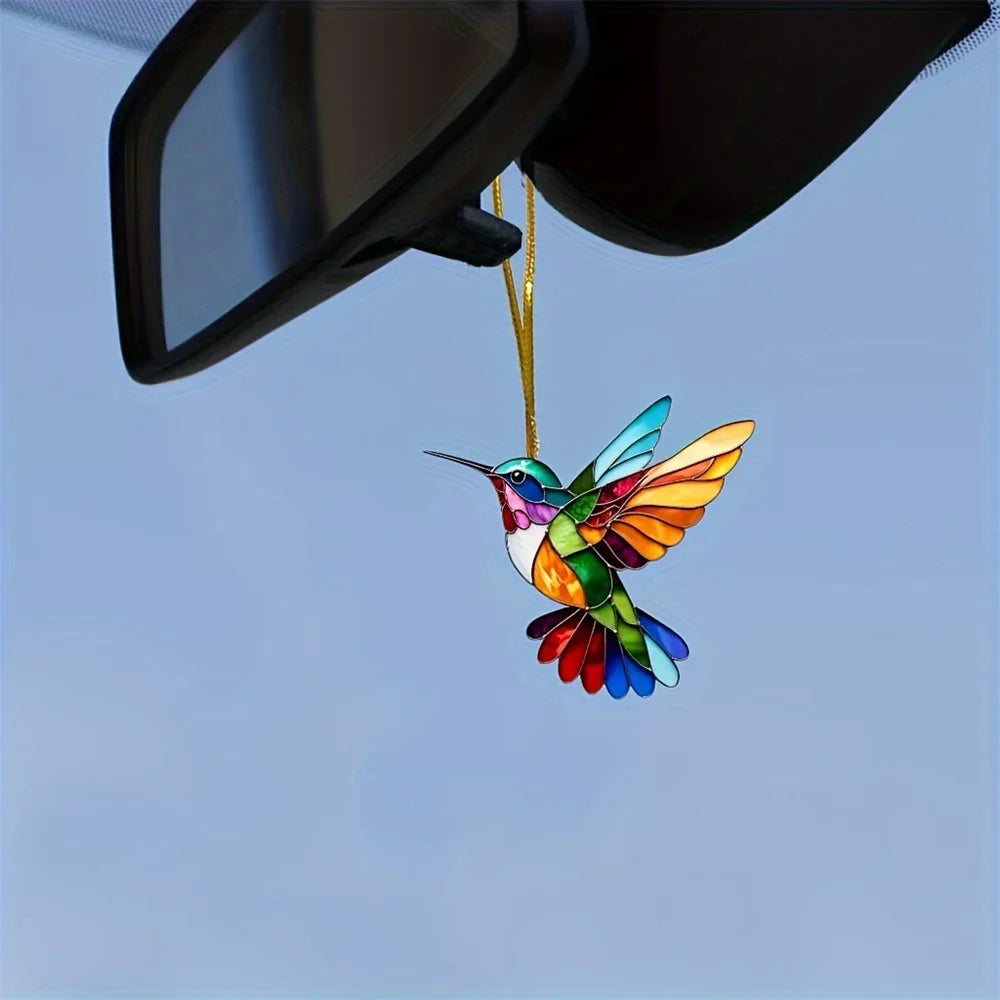 Colorful acrylic hummingbird suncatcher hanging ornament suspended against a light blue sky
