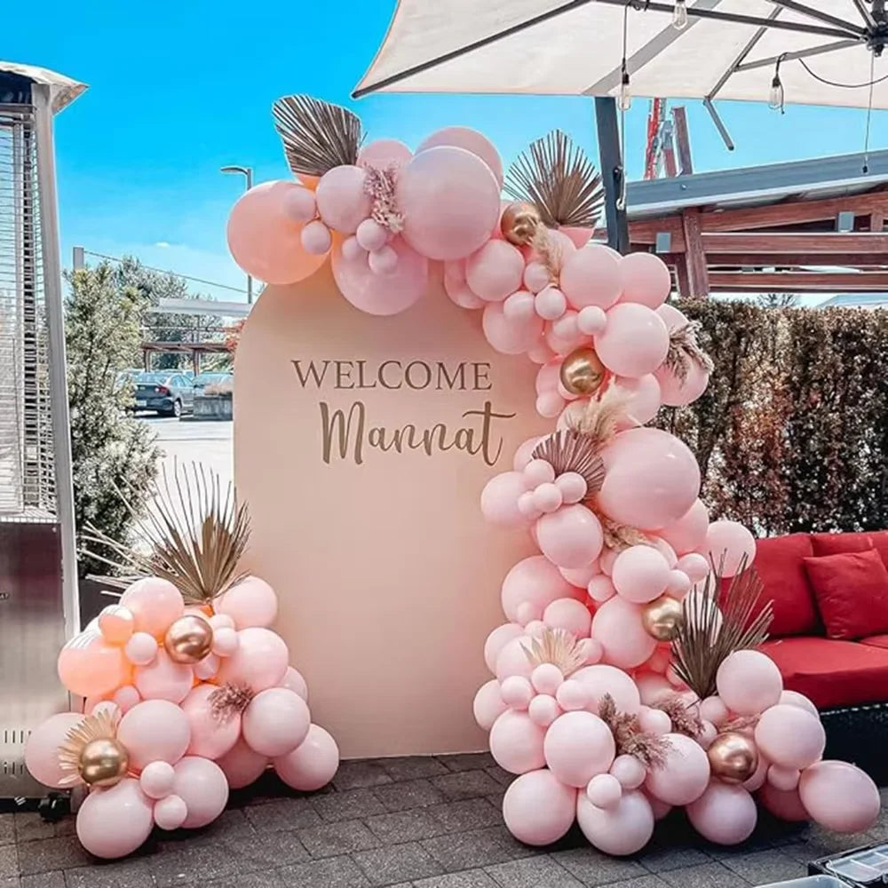 A large arrangement of pink and gold latex balloons forming a decorative archway for a celebration.