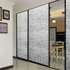 Modern interior featuring a glass partition with a white geometric pattern and black framing.
