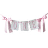 A decorative pink and white garland spelling out ONE for a first birthday celebration