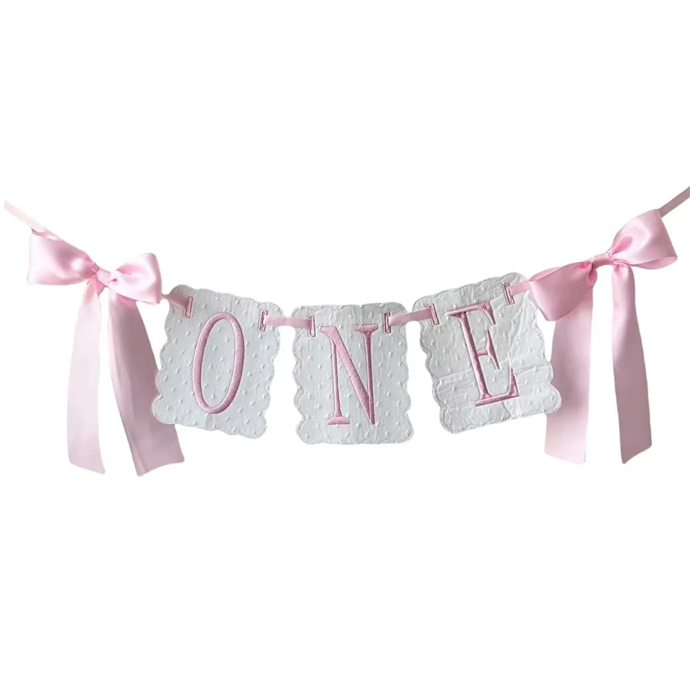 A decorative pink and white garland spelling out ONE for a first birthday celebration