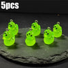 Five glow-in-the-dark green cartoon alien kitty duck resin charms displayed on a dark surface.
