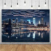 A photograph of a nighttime city skyline featuring illuminated high-rise buildings reflected in calm water under a dramatic c
