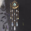 A gold flame moon crystal sun catcher featuring a crescent moon and hanging crystal beads.