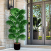 A large artificial palm tree in a black pot standing next to a glass door entrance.
