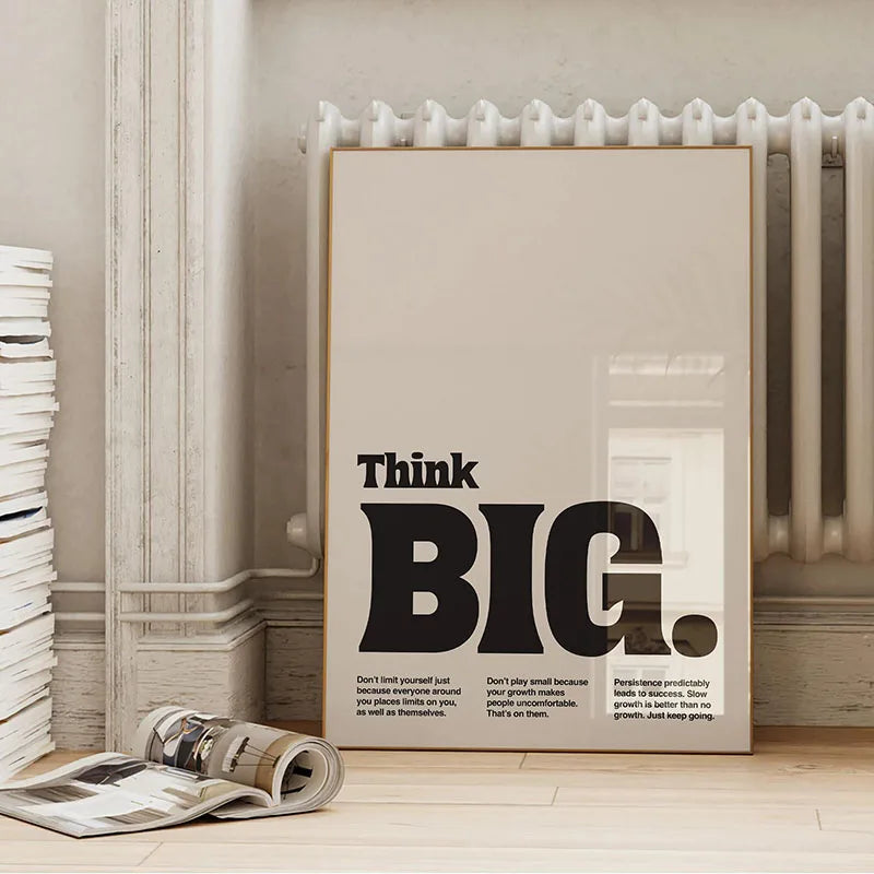 A framed canvas wall art featuring the quote Think BIG. on a light background, displayed next to a white radiator.