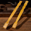 A pair of light yellow bamboo back scratchers with roller massagers resting on a wooden surface.