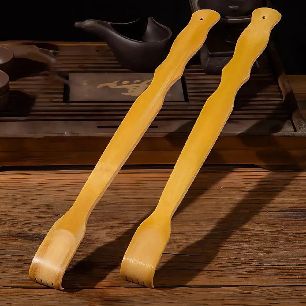 A pair of light yellow bamboo back scratchers with roller massagers resting on a wooden surface.