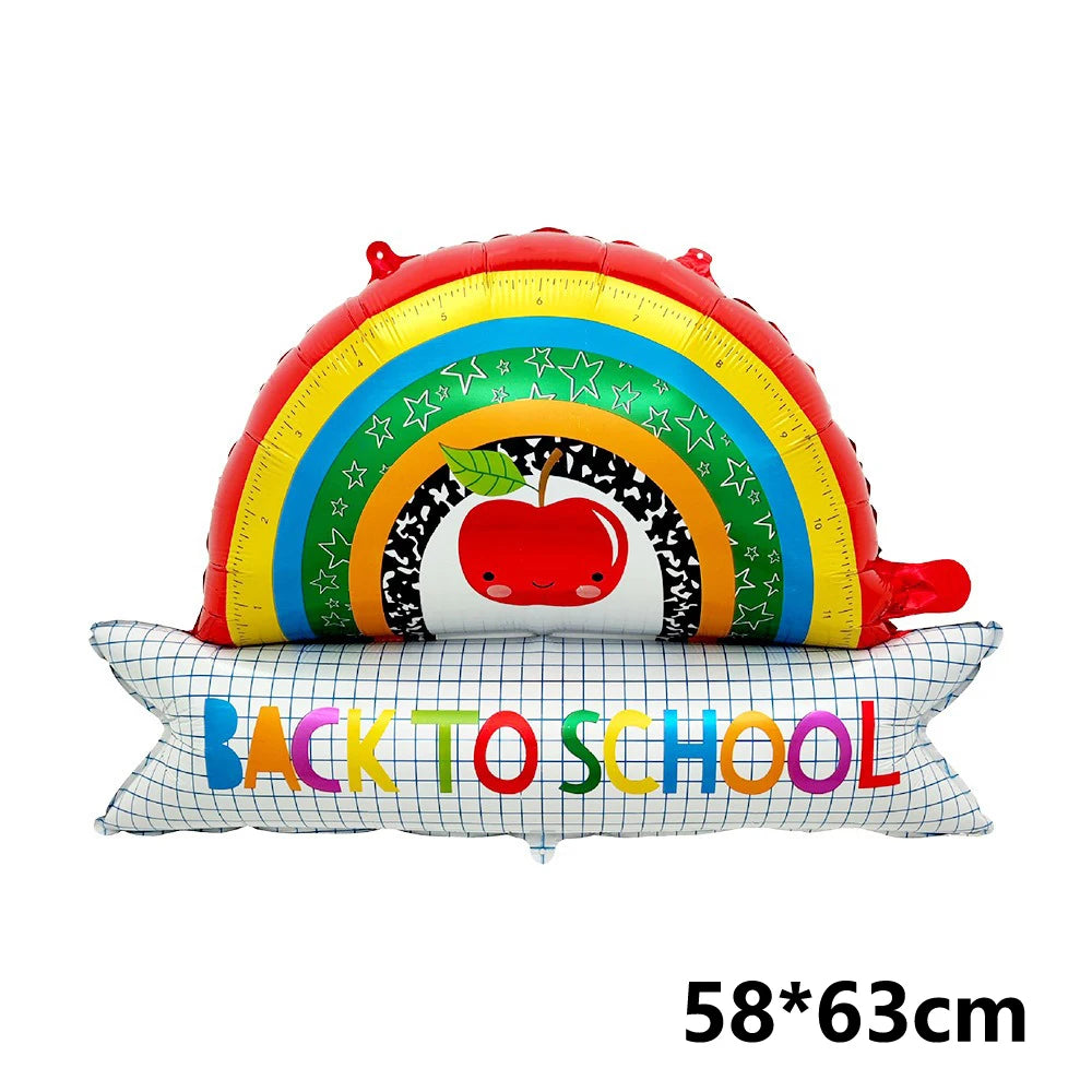 Regenbogenförmiger Folienballonbogen mit Sternen und Apfel, platziert auf einem Kissen mit der Aufschrift BACK TO SCHOOL.