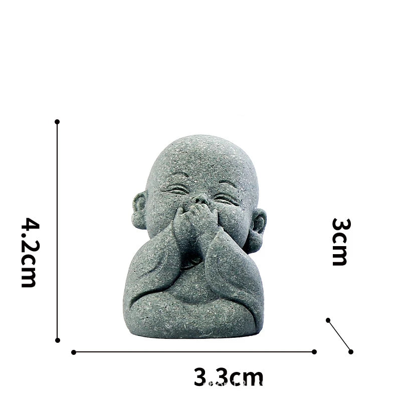A small, grey stone statue of a meditating monk with hands clasped together.