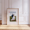 A framed photo of a bride and groom in a grassy field, displayed against white wall paneling.