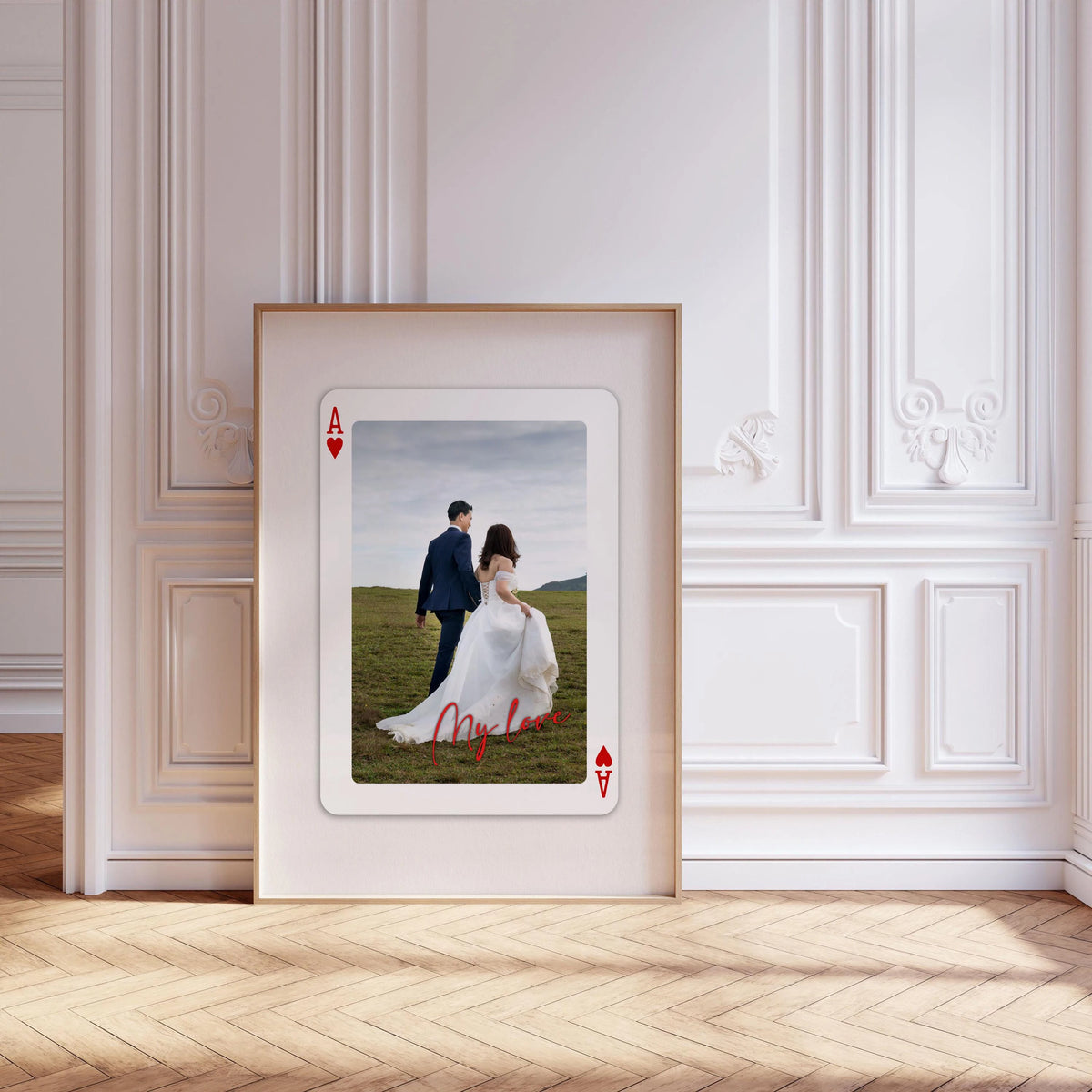 A framed photo of a bride and groom in a grassy field, displayed against white wall paneling.