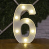 A white alphabet letter light shaped like the number six with warm white LED lights illuminating the outline.