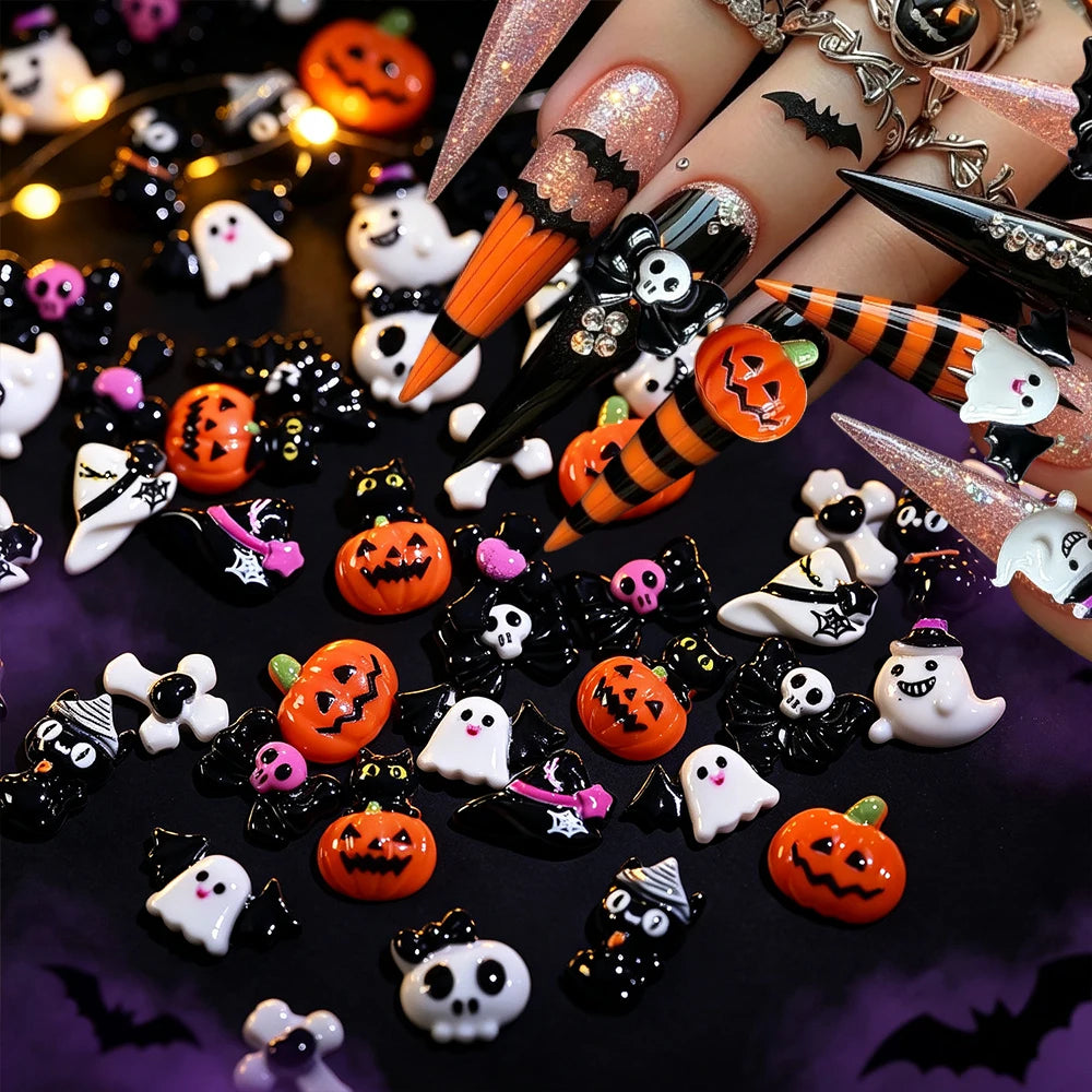 A variety pack of black and orange Halloween resin nail charms, including pumpkins, bats, and ghosts, displayed on fingers.