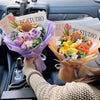 A bouquet of handmade crochet flowers in various colors is displayed in the interior of a car.