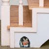 A cartoon mouse is sitting on a white wall ledge reading a book in a room with wooden stairs.