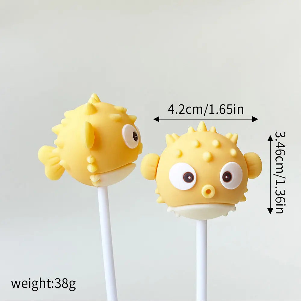 A set of yellow ocean animal cake toppers, including a whale and an octopus, mounted on white sticks.