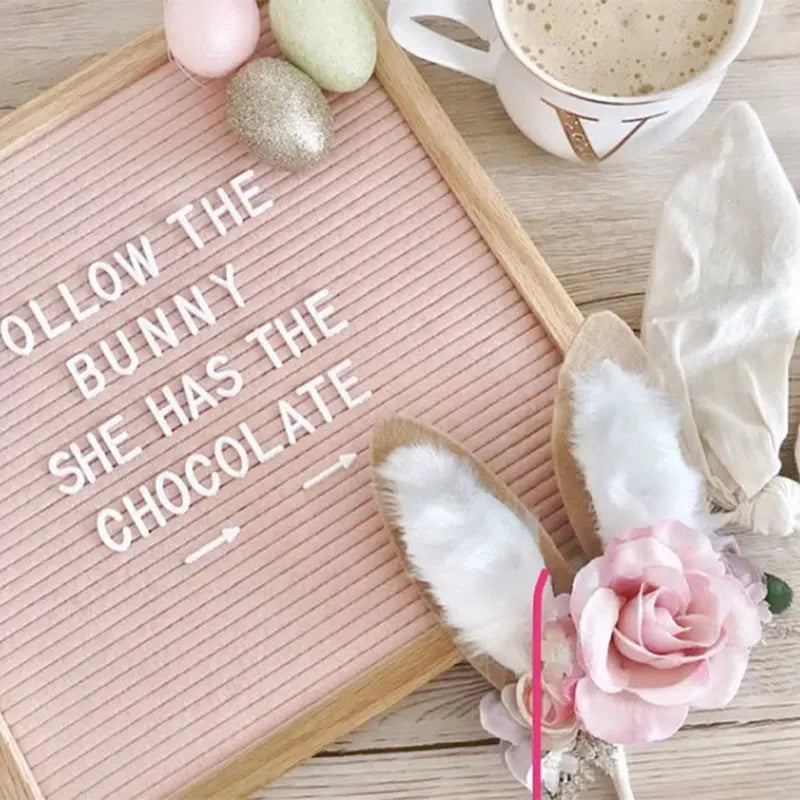 Pink felt letter board with white text instructing to follow the bunny for chocolate, next to a cup of coffee and felt bunny 