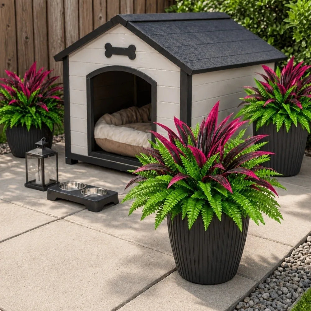 A potted artificial Dracaena Boston fern with vibrant pink and green leaves sits in front of a wooden shed.