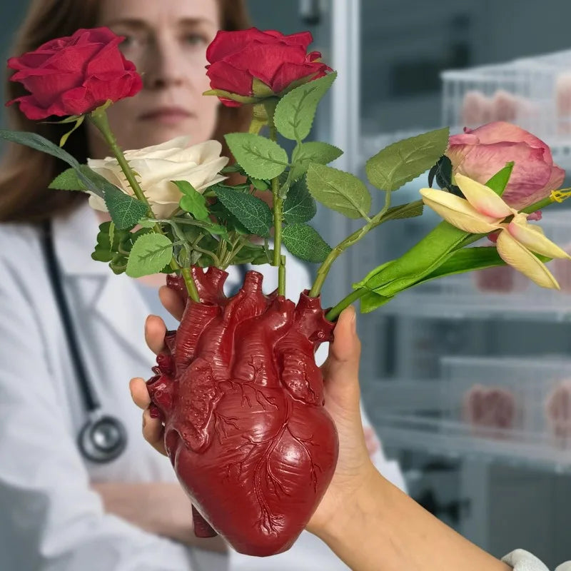 A hand holds a realistic, heart-shaped resin model of a human heart with gold accents.