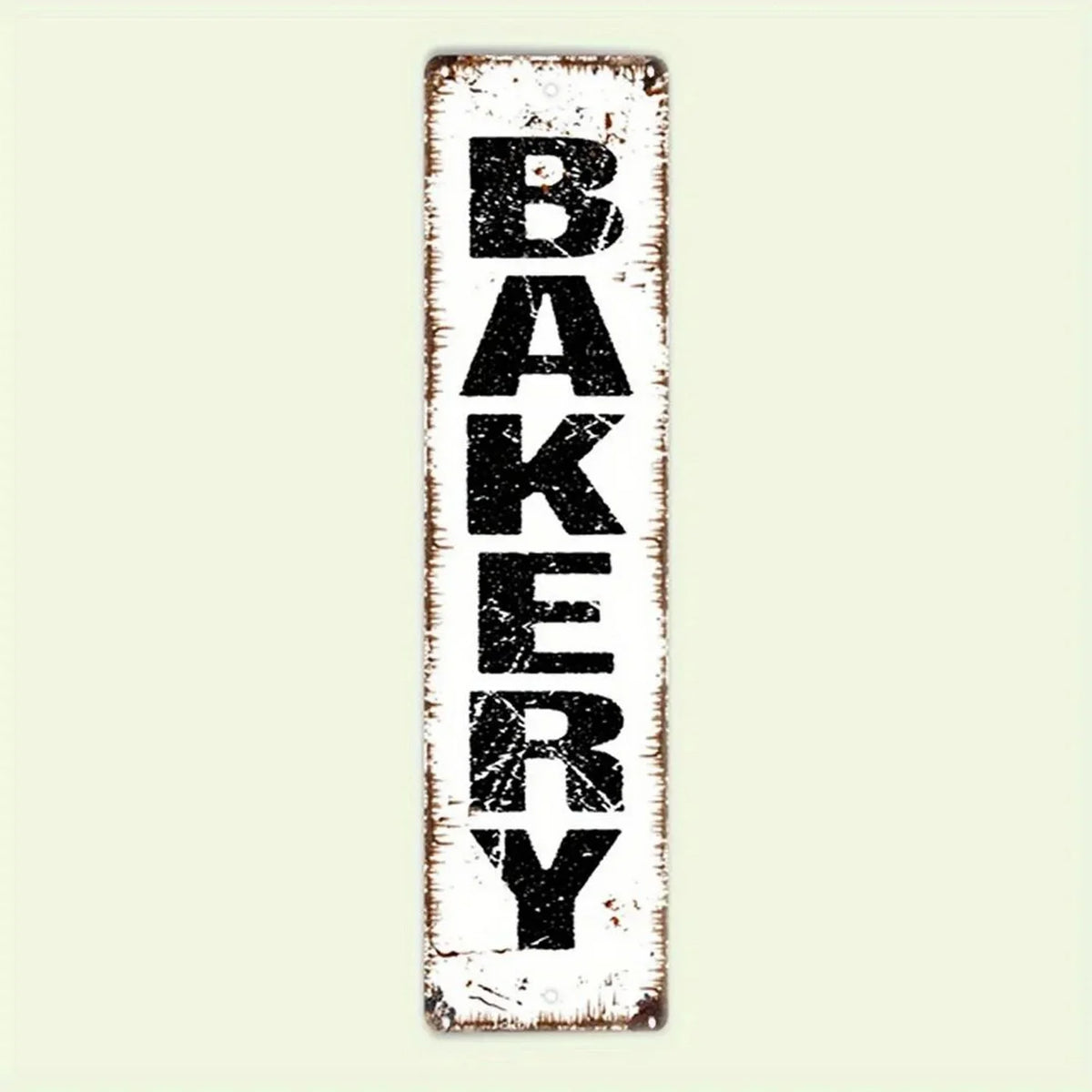 A distressed white metal sign with the word BAKERY painted in black block letters.