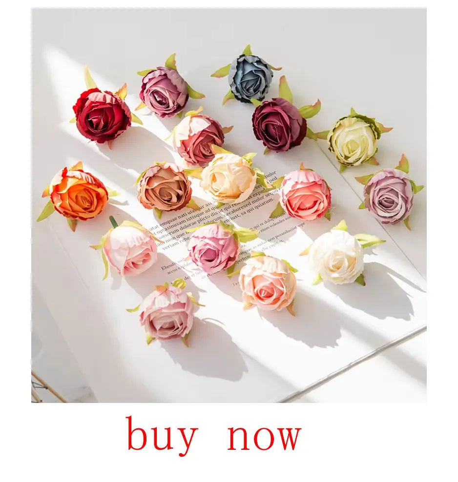 A collection of artificial rose-colored eucalyptus leaves in various shades of pink, red, and green arranged on white paper.