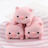 Three pink pig mochi squishy stress relief toys are displayed on a striped surface.