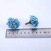 Un amas de fleurs artificielles bleu hydrangee à côté d'une règle pour l'échelle.