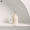 A tall, cylindrical ceramic vase in a light beige color displayed on a white shelf.