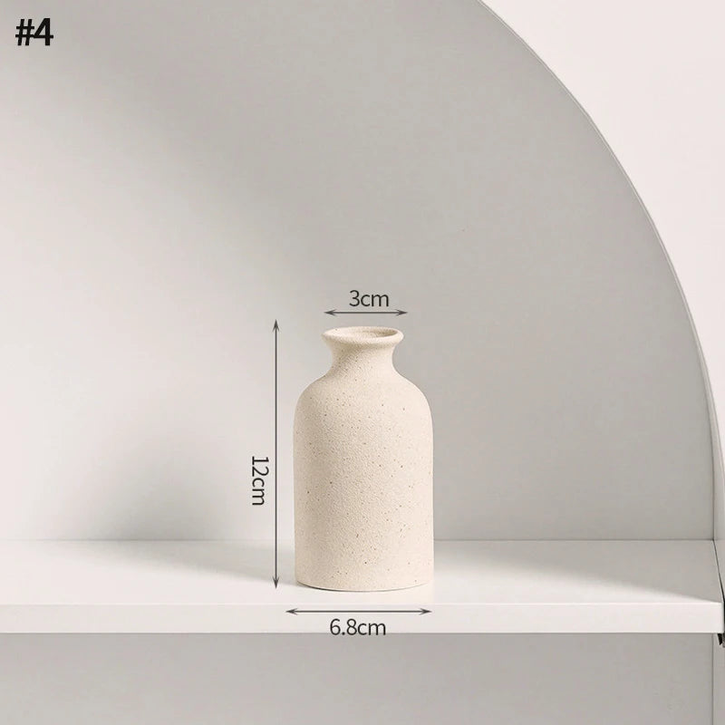 A tall, cylindrical ceramic vase in a light beige color displayed on a white shelf.