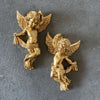A pair of golden cherub angels wall decor set with wings and draped fabric.